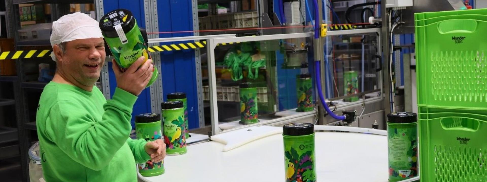 John aan het werk met het vullen van de koffieblikken