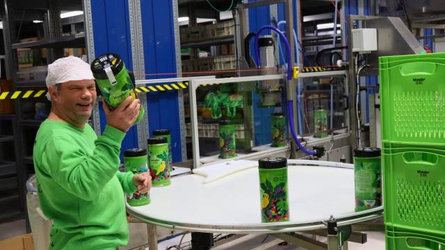 John aan het werk met het vullen van de koffieblikken